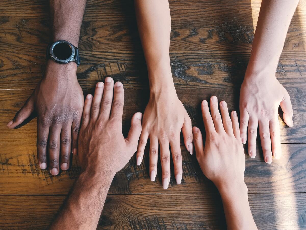 Five Hands backs from five different person over a table